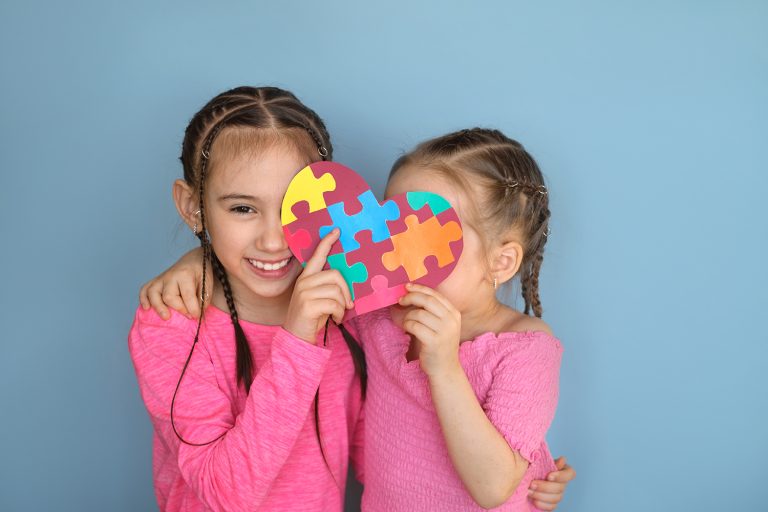 Shy kids hide their faces behind large heart with multicolored grooves inside
